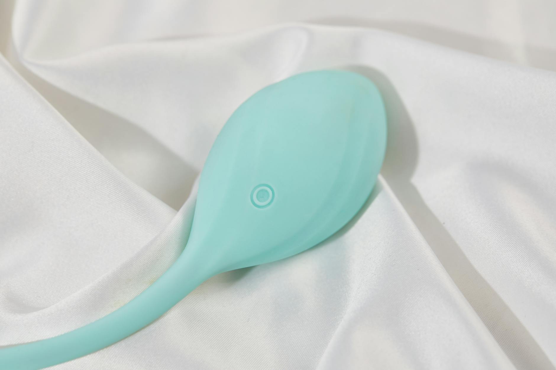 Mano sosteniendo un vibrador azul de silicona contra fondo sólido púrpura, promoviendo la salud sexual y el amor propio