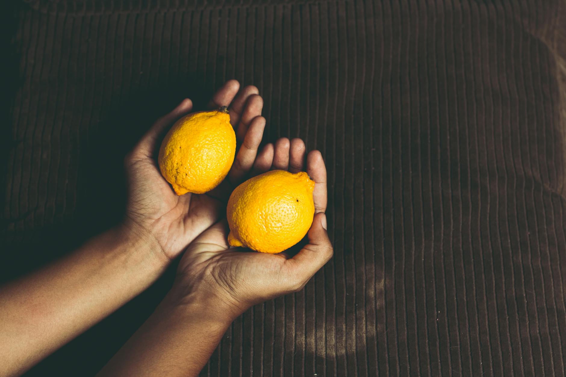 Close-up of fresh lemons in cupped hands, symbolizing the gentle touch of a lemon vibrator experience