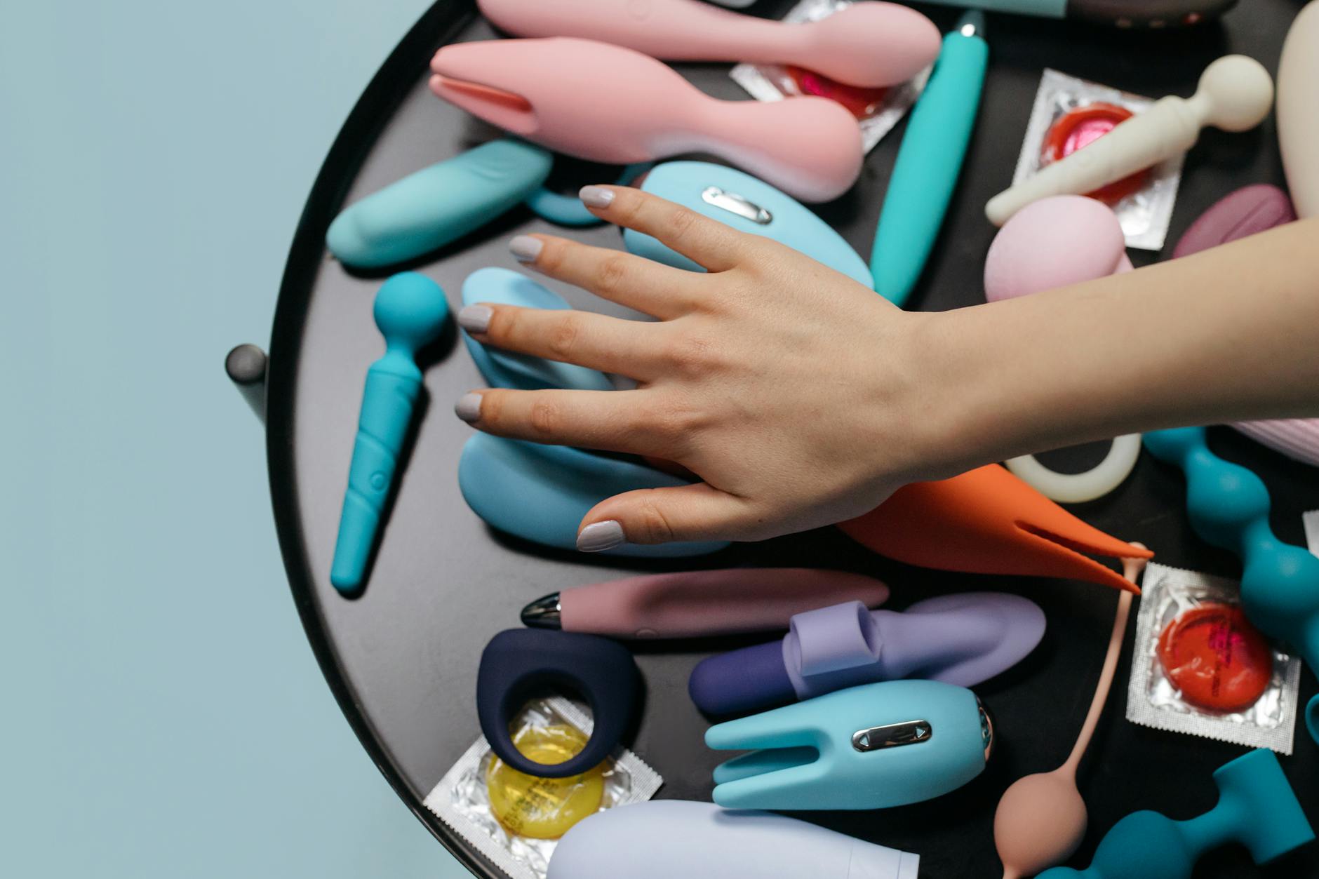 Una mujer sosteniendo un vibrador rosa con libros de arte de fondo, enfatizando temas íntimos y personales.
