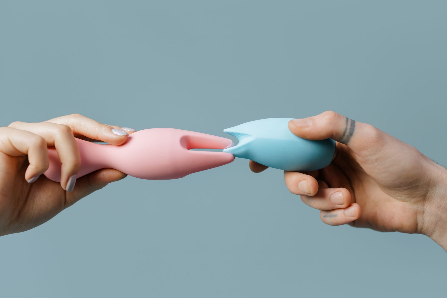 Manos sosteniendo juguetes sexuales de silicona pastel, perfectos para temas de estilo de vida y placer adulto