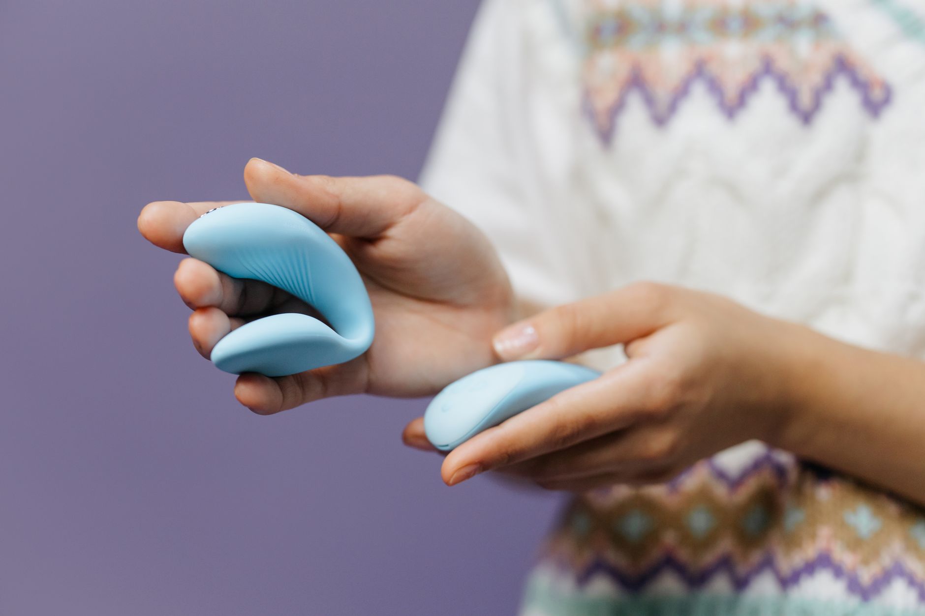 Mano sosteniendo un vibrador de limón azul contra un fondo púrpura