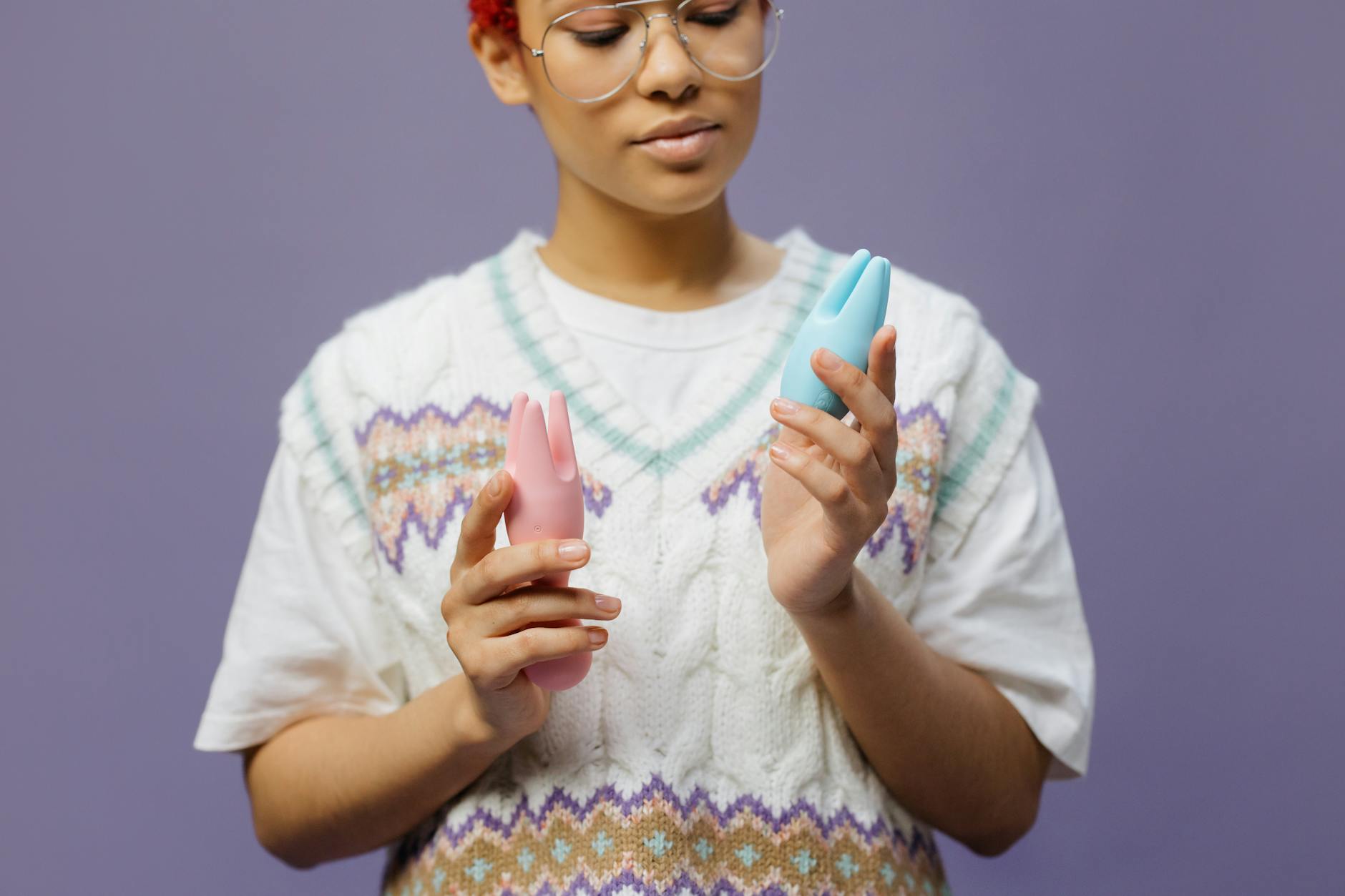 Mujer sosteniendo vibradores de silicona de colores pastel en un momento reflexivo de descubrimiento